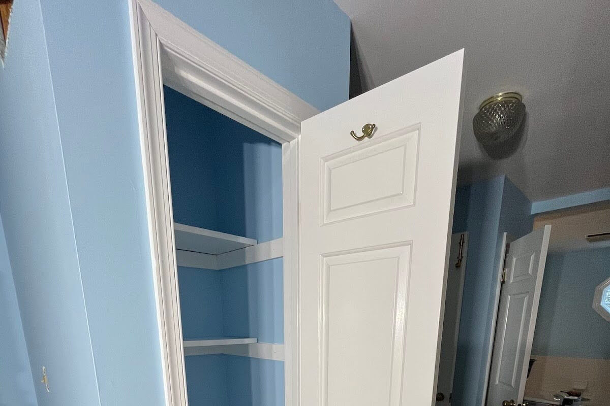 An opened closet door with blue walls.